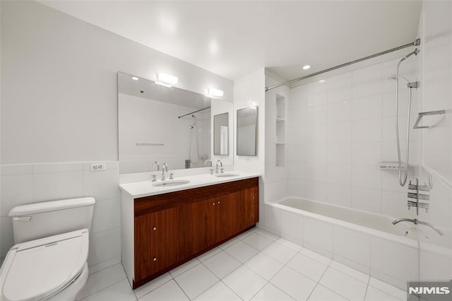 bathroom with tile patterned floors, toilet, tiled shower / bath, and a sink