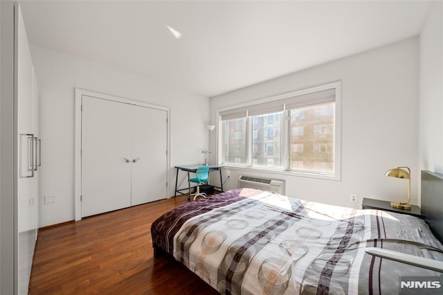 bedroom featuring a closet, a wall mounted AC, and wood finished floors