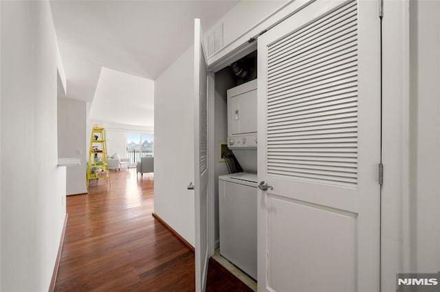 hall with dark wood-style flooring, baseboards, and stacked washer and dryer