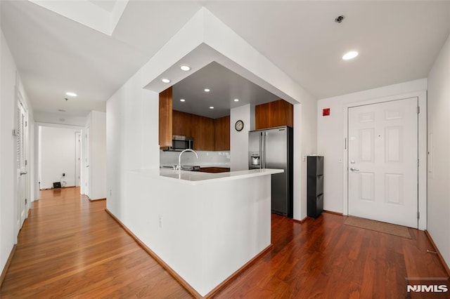 kitchen featuring a sink, light countertops, dark wood-style flooring, and stainless steel appliances