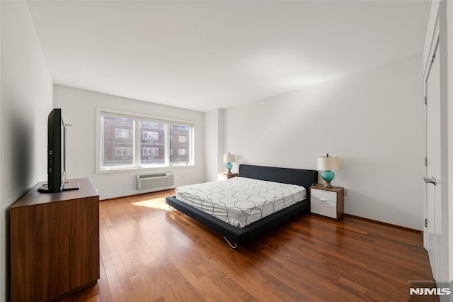 bedroom featuring a wall unit AC and wood finished floors