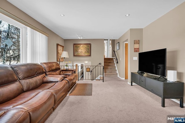 living room featuring baseboards, recessed lighting, stairs, and light colored carpet