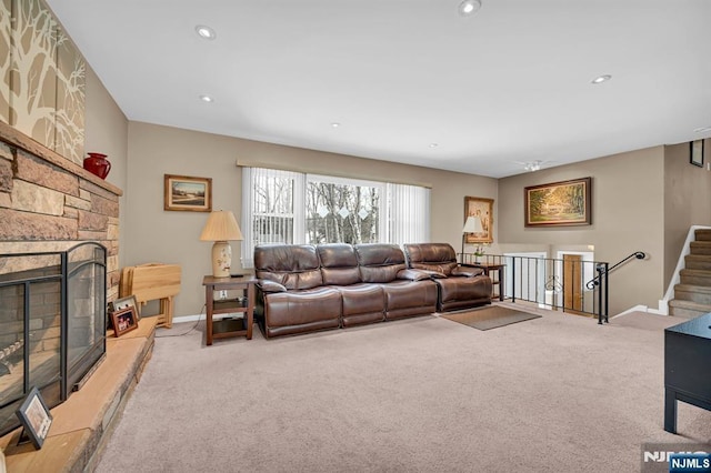 living area featuring light carpet, a fireplace, and baseboards