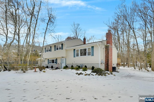 split level home featuring a garage, a chimney, and cooling unit