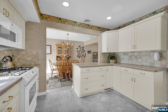 kitchen featuring a peninsula, white appliances, visible vents, hanging light fixtures, and light countertops