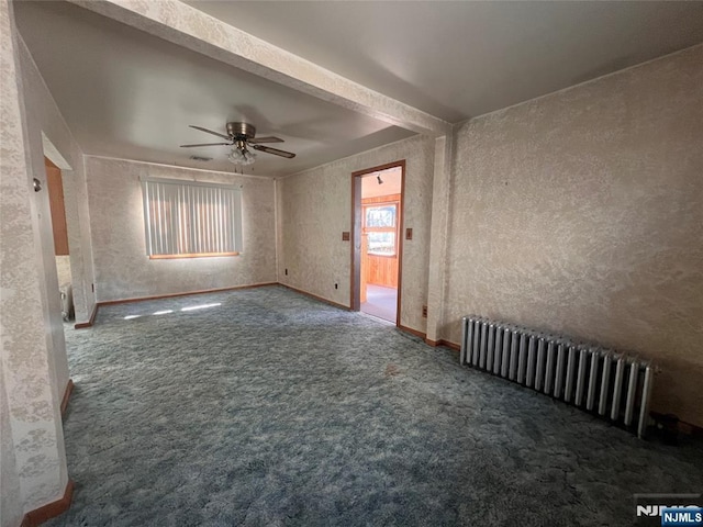 carpeted empty room with ceiling fan and radiator