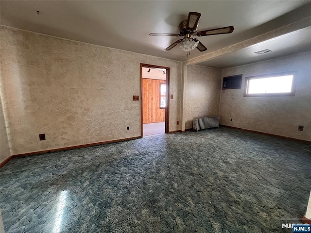 carpeted empty room with radiator and ceiling fan