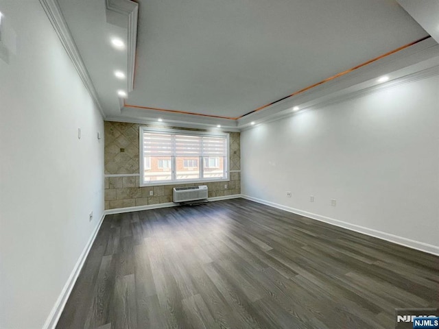 unfurnished living room featuring an AC wall unit, dark wood-type flooring, and crown molding