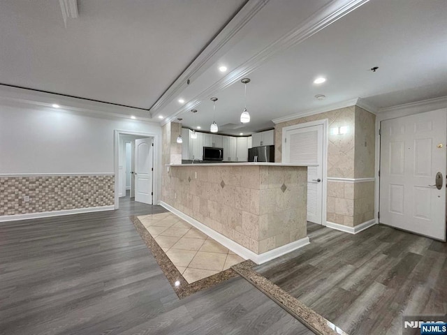 kitchen with white cabinetry, kitchen peninsula, ornamental molding, and stainless steel fridge