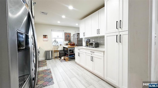 kitchen with white cabinetry, stainless steel fridge, and decorative backsplash