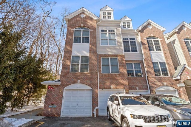 view of property featuring a garage, driveway, and brick siding