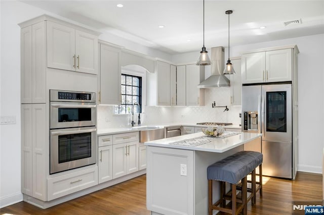 kitchen with appliances with stainless steel finishes, extractor fan, a center island, sink, and white cabinetry