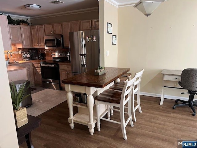 dining area with hardwood / wood-style floors, sink, and ornamental molding