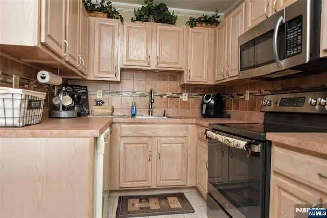 kitchen with appliances with stainless steel finishes, decorative backsplash, sink, and light brown cabinetry
