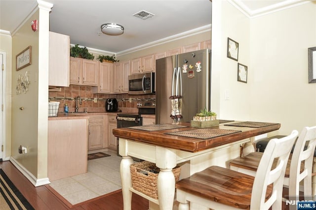 kitchen featuring stainless steel appliances, backsplash, crown molding, and light brown cabinetry