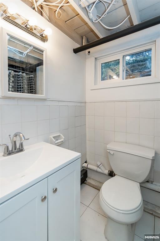 bathroom featuring tile walls, vanity, tile patterned floors, and toilet