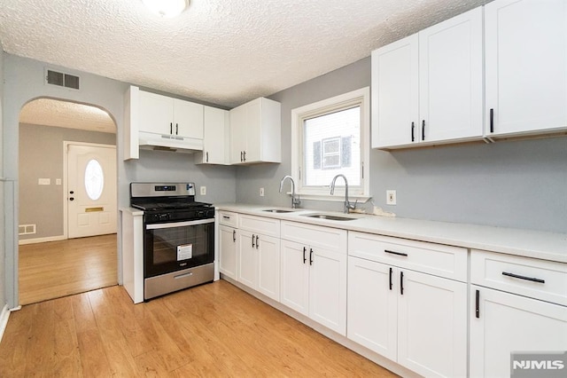 kitchen with white cabinetry, sink, stainless steel gas range, and light hardwood / wood-style flooring