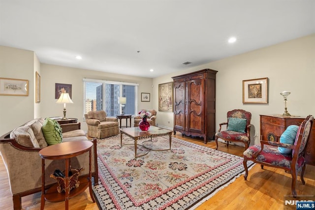 living room with light wood finished floors, visible vents, and recessed lighting