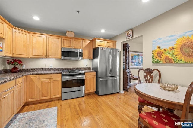 kitchen with stainless steel appliances, recessed lighting, dark countertops, and light wood-style floors