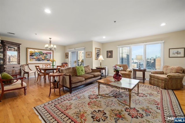 living room with light wood-style flooring, recessed lighting, a notable chandelier, visible vents, and baseboards