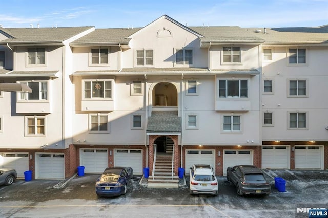 view of property with an attached garage, driveway, and stairway