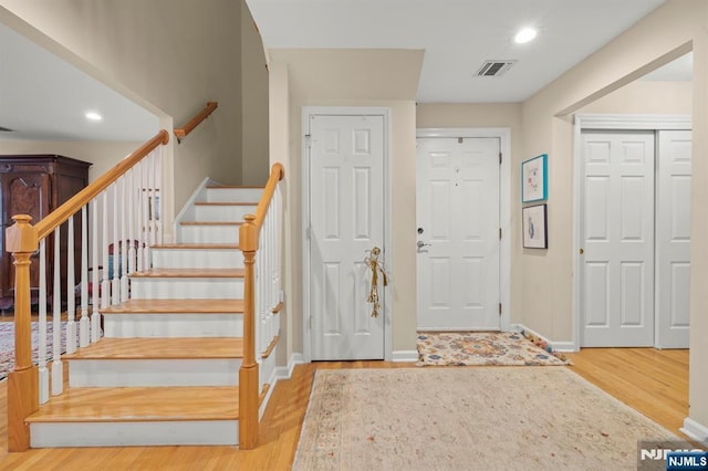 entryway featuring stairway, visible vents, light wood-style flooring, and baseboards