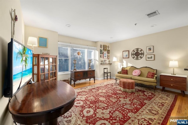 living room with visible vents, baseboards, and wood finished floors