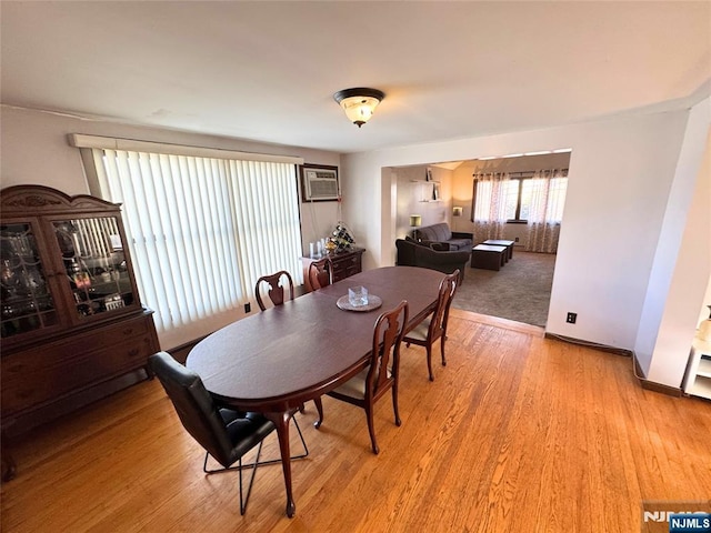 dining area with a wall mounted AC and light hardwood / wood-style floors