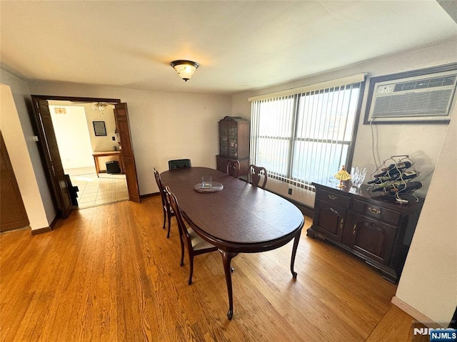 dining area featuring an AC wall unit and light wood-type flooring