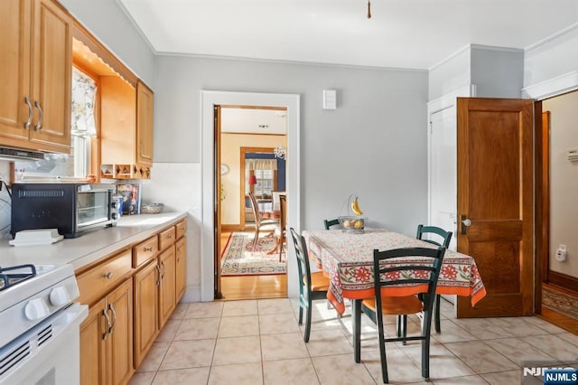 kitchen featuring a toaster, light countertops, crown molding, and light tile patterned floors