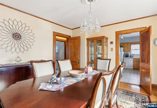 dining space with a notable chandelier, light wood-style flooring, and crown molding