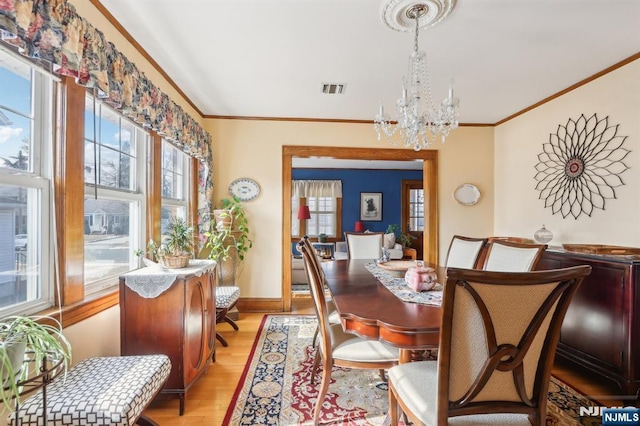 dining area with crown molding, light wood finished floors, visible vents, a chandelier, and baseboards