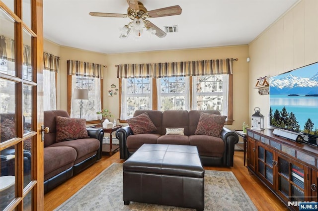 living room featuring a baseboard radiator, wood finished floors, visible vents, and a ceiling fan