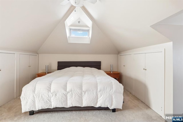 bedroom featuring multiple closets, light colored carpet, and vaulted ceiling