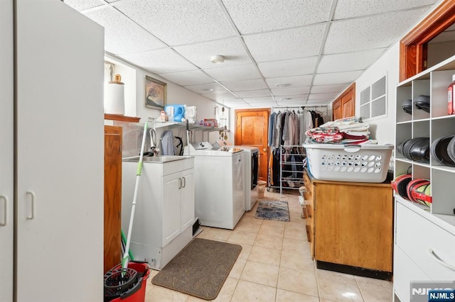 washroom with cabinet space, washing machine and clothes dryer, and light tile patterned floors