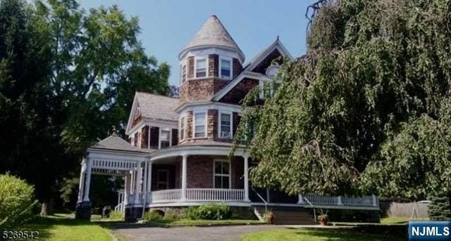 rear view of house with covered porch and a lawn