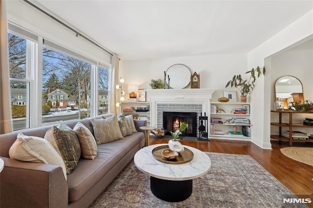 living room with dark hardwood / wood-style floors and a brick fireplace