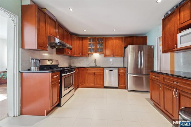 kitchen with tasteful backsplash, sink, dark stone counters, and appliances with stainless steel finishes