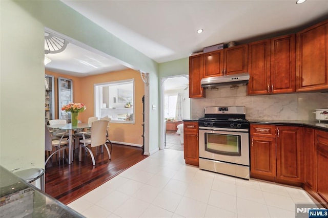 kitchen with gas range, dark stone counters, light tile patterned flooring, and tasteful backsplash