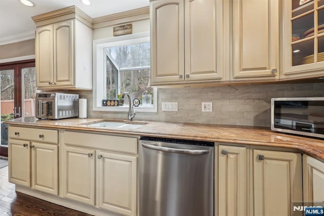 kitchen with a sink, tasteful backsplash, appliances with stainless steel finishes, and cream cabinetry