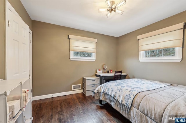 bedroom with dark wood-style flooring, visible vents, and baseboards