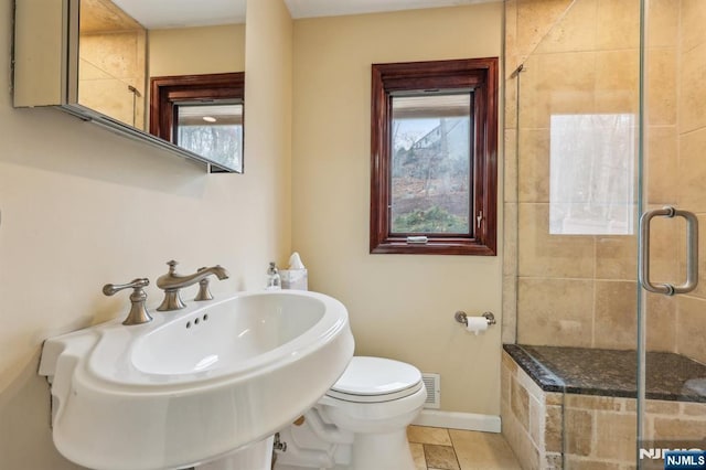 full bathroom with visible vents, toilet, a sink, a shower stall, and baseboards