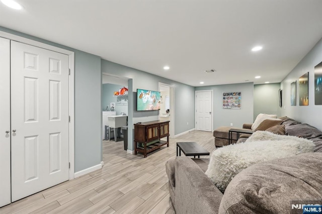 living room with light wood-style flooring, visible vents, baseboards, and recessed lighting