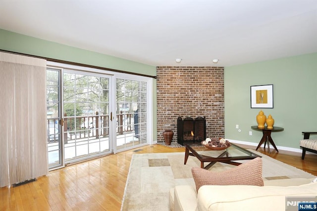 living room featuring a brick fireplace and light hardwood / wood-style floors