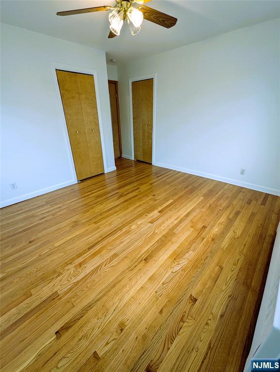 spare room with a ceiling fan, light wood-type flooring, and baseboards