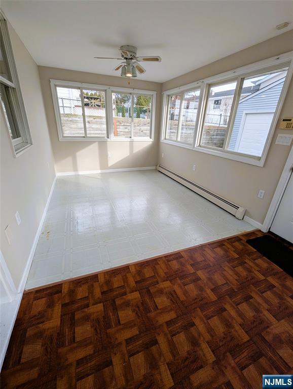 unfurnished sunroom with plenty of natural light, ceiling fan, and a baseboard radiator