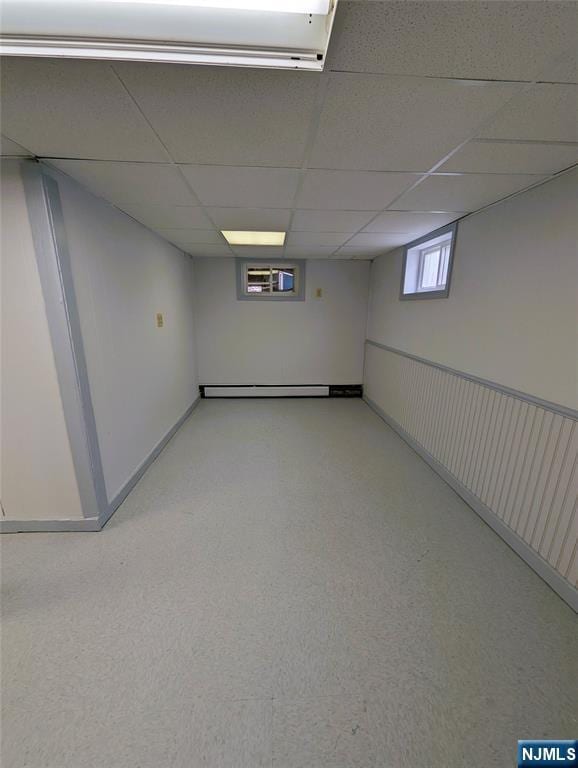 basement featuring a baseboard radiator and a drop ceiling