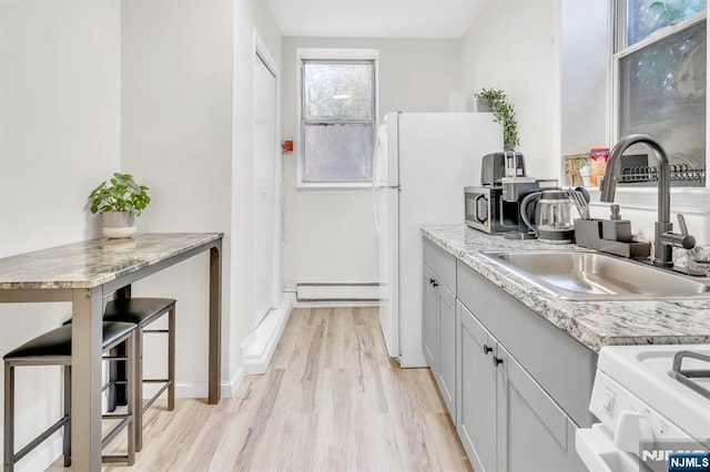 kitchen with sink, white appliances, and light hardwood / wood-style flooring