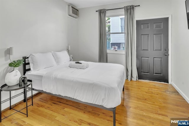 bedroom featuring hardwood / wood-style floors and a wall unit AC