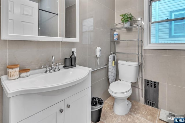 bathroom with vanity, toilet, radiator, and tile walls